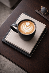 Black  Coffee mug with latte art on a stack of books on a wooden surface
